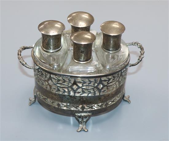 A George V pierced silver two handled scent bottle stand, Birmingham, 1928 with four mounted glass flasks, Birmingham, 1922